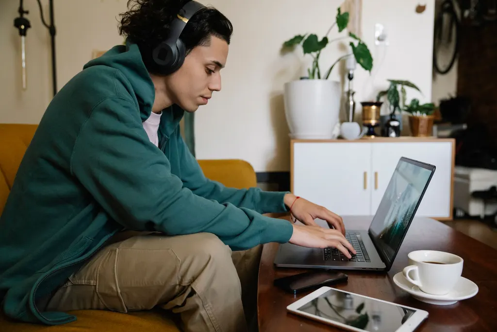 Colaborador latino con audífonos concentrado en laptop, adaptándose a distintas dinámicas