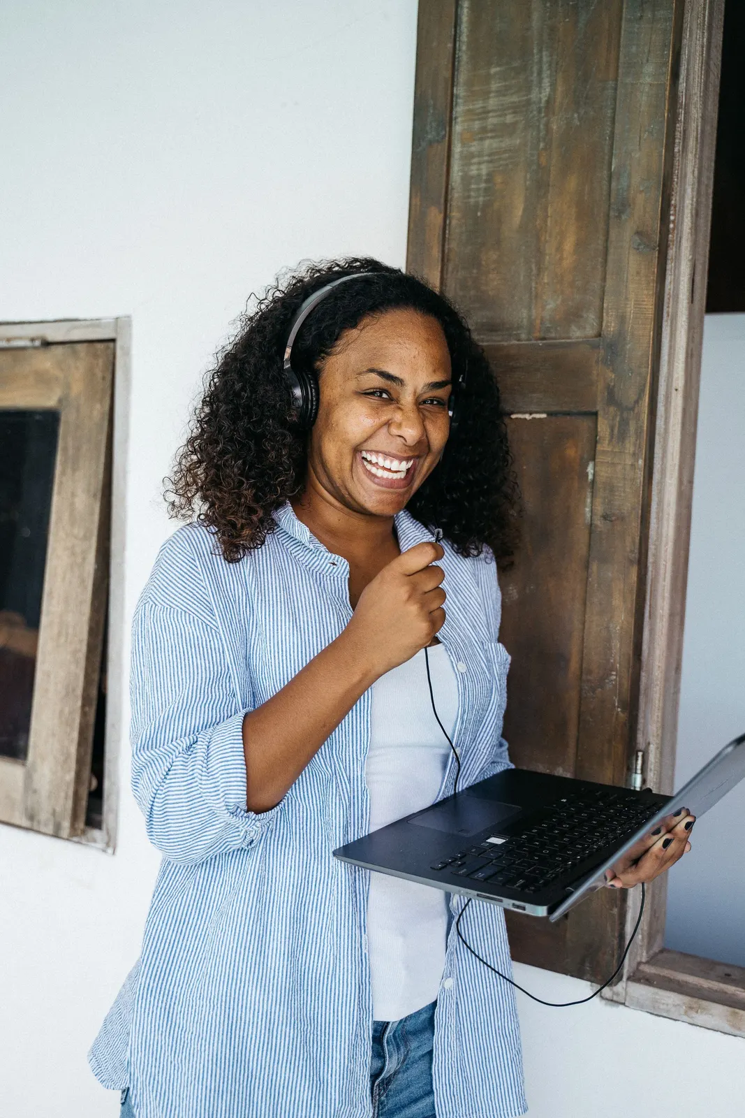 Asistente latina feliz con audífonos y laptop desde su oficina en casa