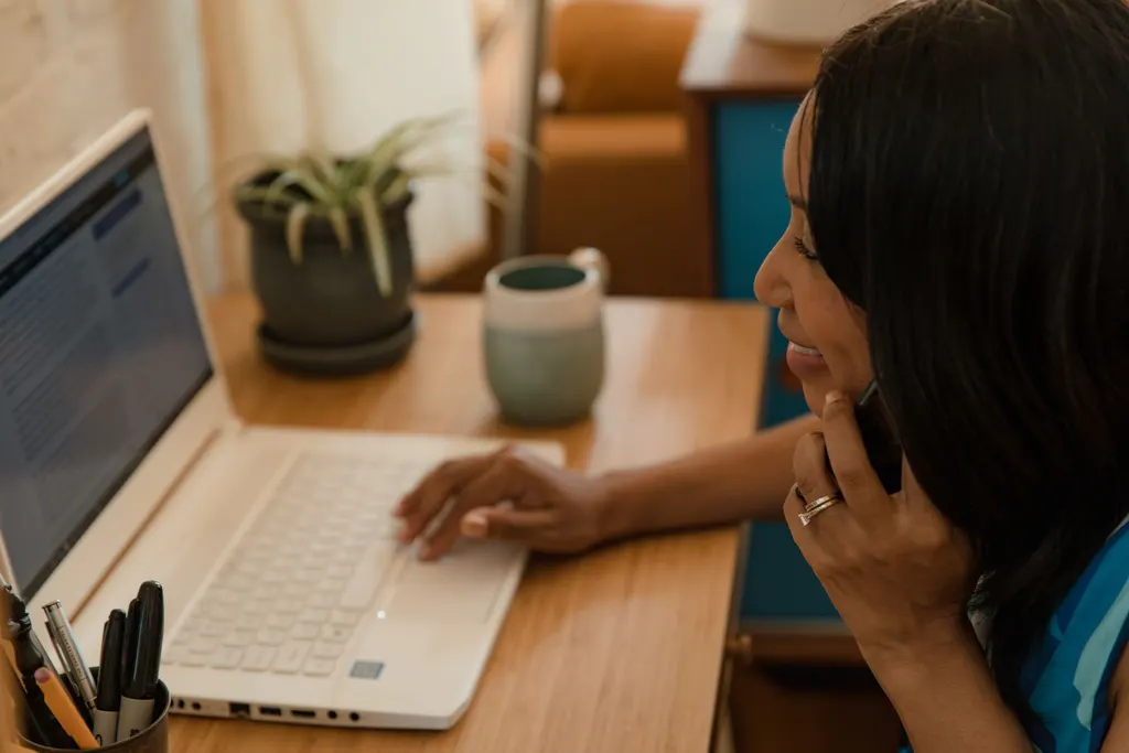 Asistente virtual latina gestionando llamadas y laptop desde casa